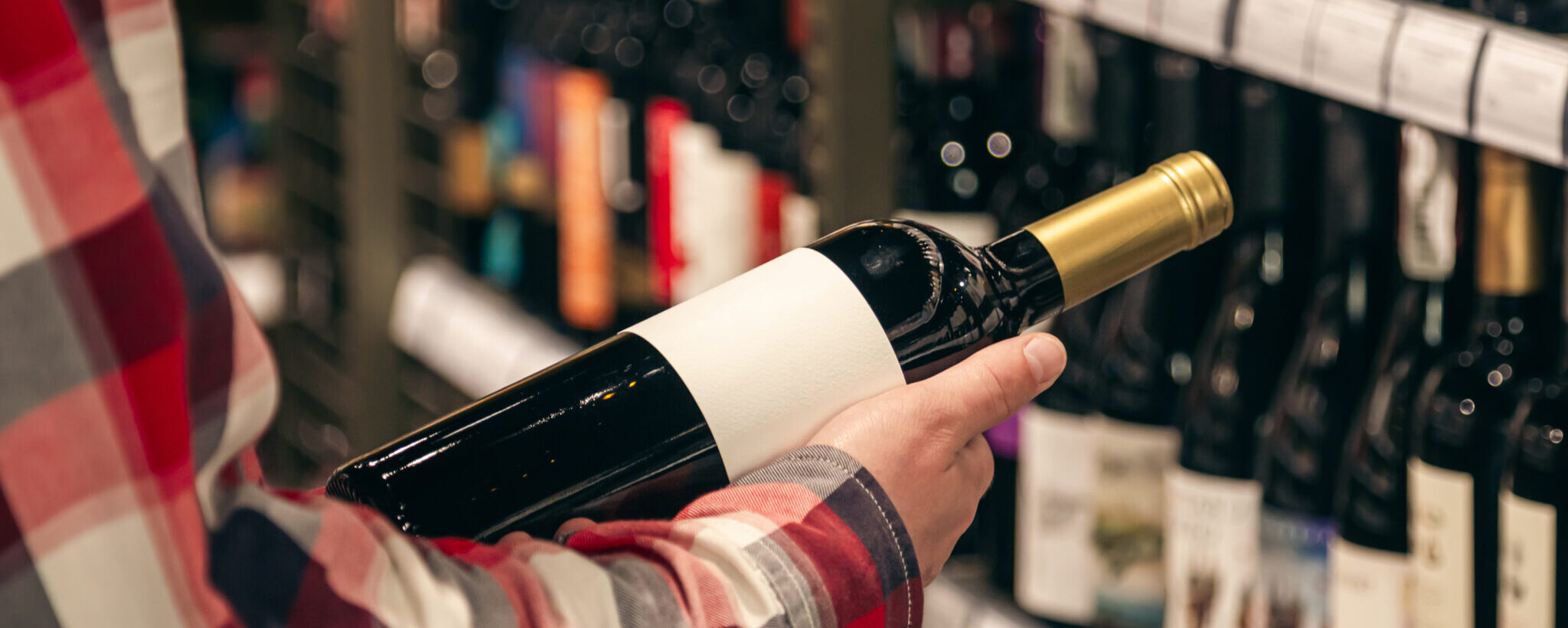 A Male Customer Holding A Bottle Of Red Wine, Close Up.